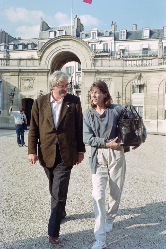did jane birkin design the birking bag, French director Bertrand Tavernier and French actress and singer Jane Birkin arrive at the Elysée Palace where they are received by the President of the Republic François Mitterrand  before the 43rd Cannes Film Festival, on May 9, 1990. (Photo by Gilles LEIMDORFER / AFP) (Photo by GILLES LEIMDORFER/AFP via Getty Images)