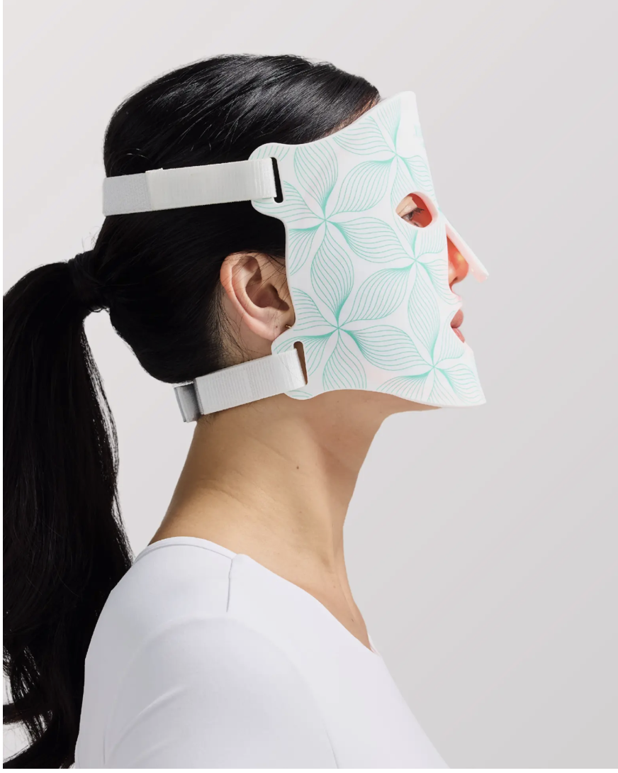 woman wearing omnilux contour face mask while standing sideways and having her hair in a ponytail