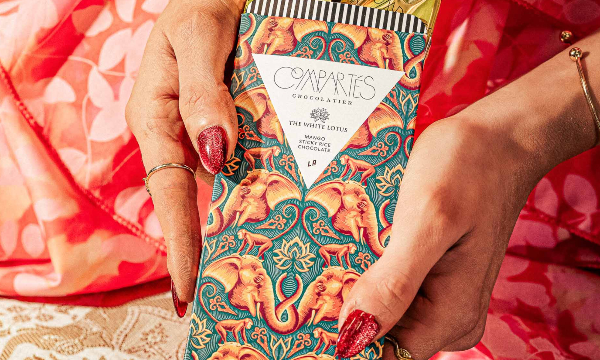 Compartés x The White Lotus chocolate bar held up in someone's manicured hands