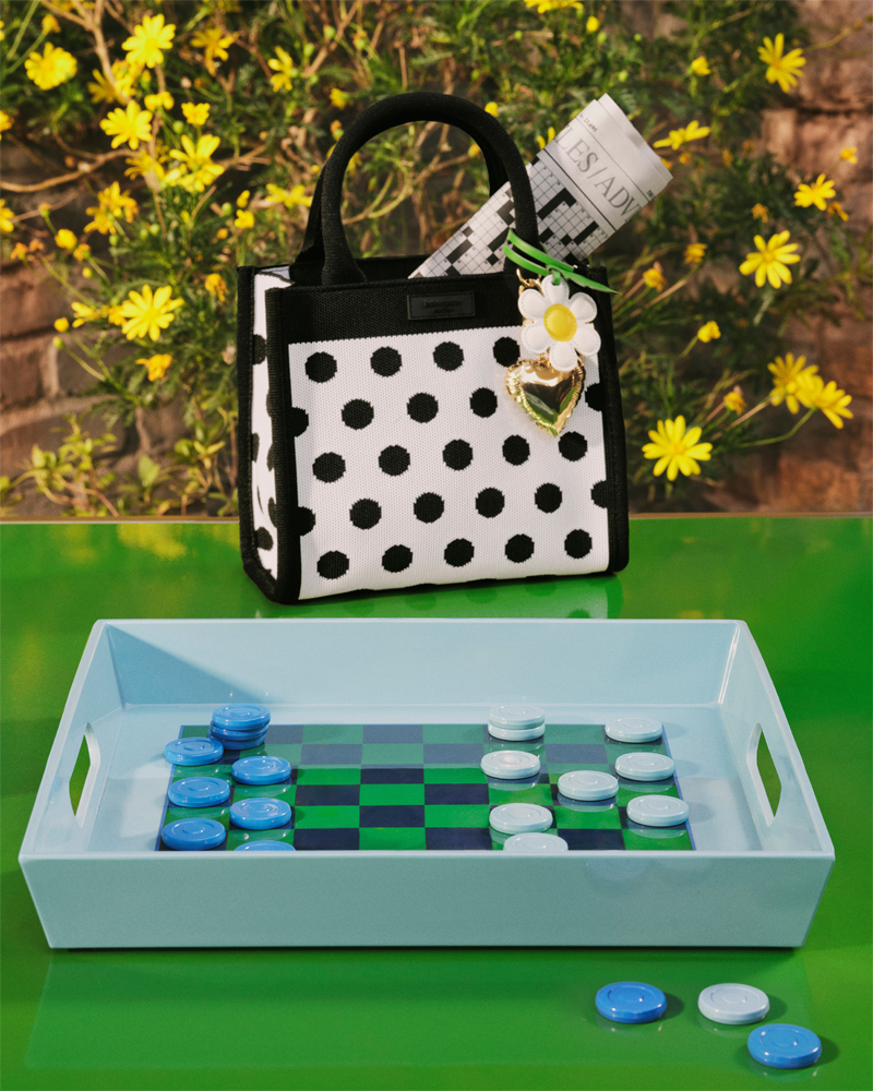 polka-dotted bag resting on glossy green table next to a checkers set