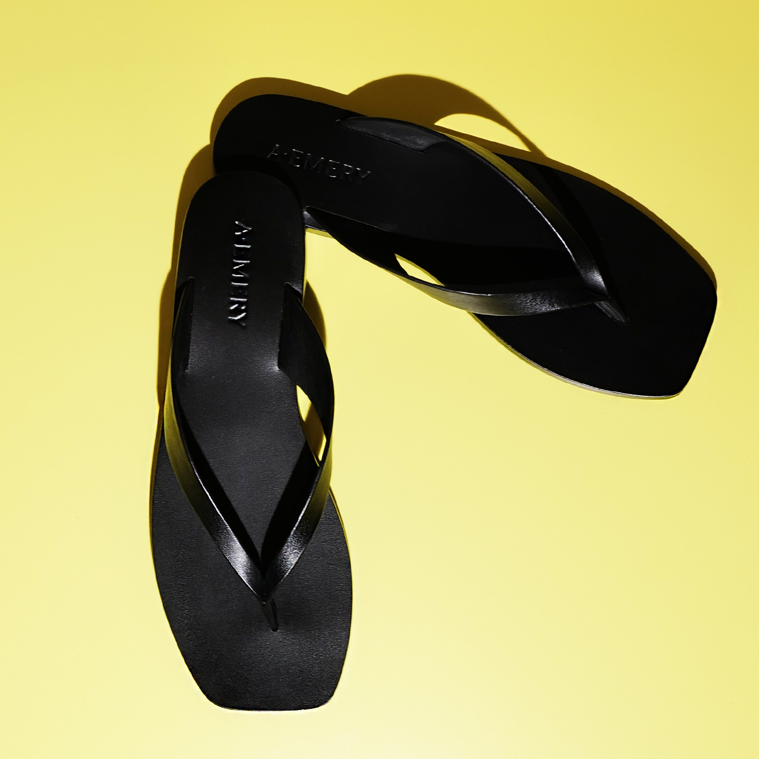A. Emery Kinto Sandals in black on yellow backdrop