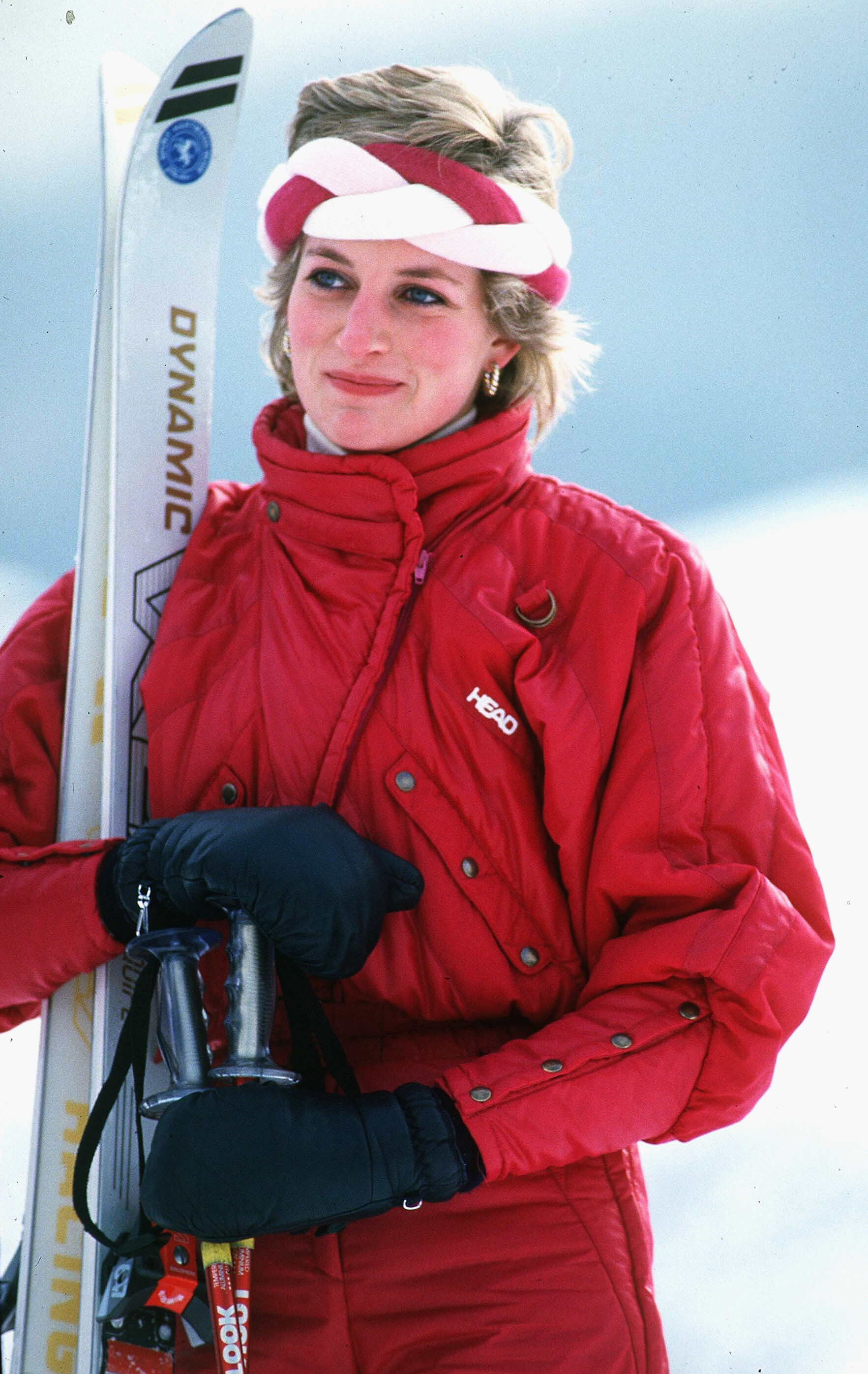 KLOSTERS, SWITZERLAND - FEBRUARY 06: Diana, Princess of Wales, wearing a red ski suit by Head and a braided headband, holds her skis and poles during a holiday in Klosters on February 6, 1986 in Klosters, Switzerland. (Photo by Anwar Hussein/WireImage)